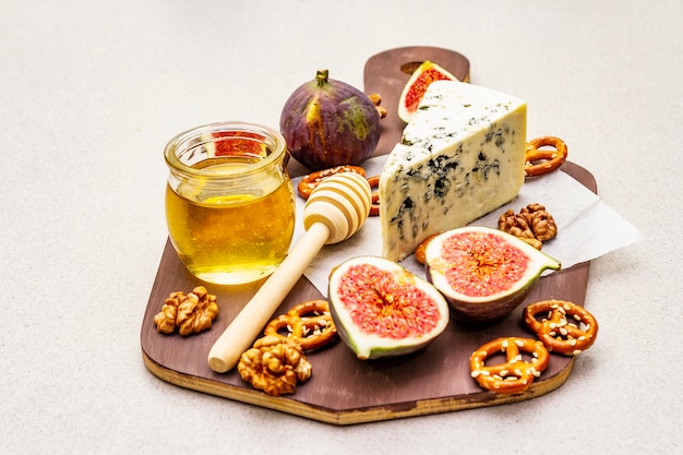 Prato de queijos (tábua) com queijo azul, mel, nozes, figos, pretzels