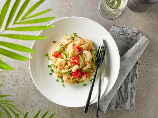 Prato de risoto com abobrinha e camarões na vista de mesa de restaurante cinza