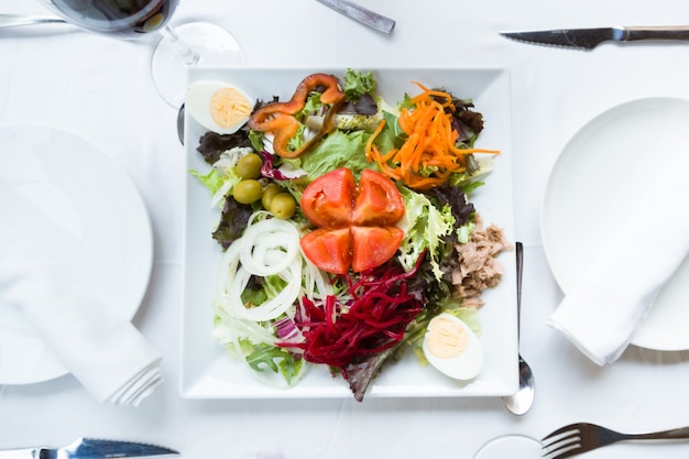 Prato de salada com legumes frescos, ovos cozidos, atum e azeitonas verdes.