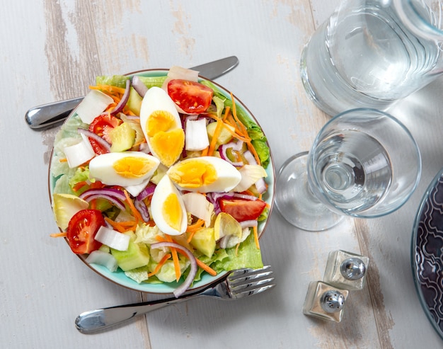 Prato de salada de legumes na mesa de madeira branca