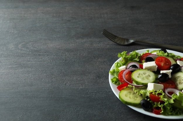 Prato de salada grega e garfo em madeira escura