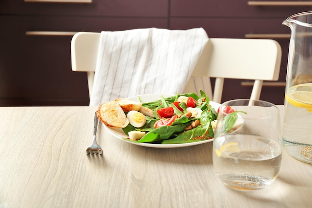 Prato de salada saborosa com folhas de espinafre na mesa de madeira