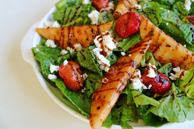 Prato de salada verde com peras assadas e morangos frescos