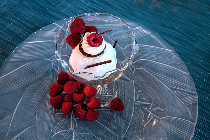 Foto prato de sobremesa de bolo de queijo, chocolate raspado e framboesas em um prato de vidro