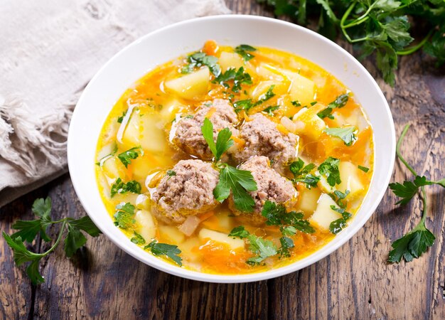 Prato de sopa com almôndegas na mesa de madeira