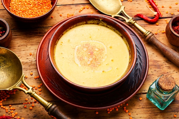 Prato de sopa vegetariana de lentilha vermelha na mesa de madeira