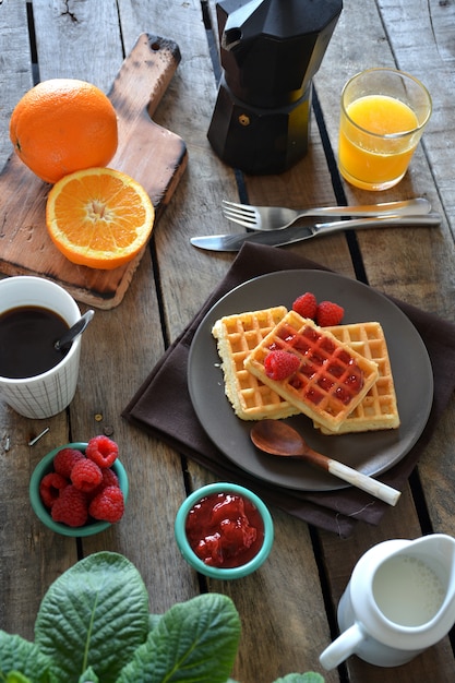 Prato de waffles com marmelada de framboesa, suco de laranja e café