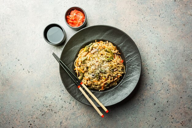 Prato de wok ou macarrão frito com carne e vegetais sobre pedra cinza