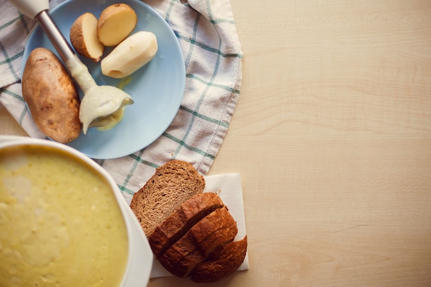 Prato fundo de purê de batata e fatias de pão de centeio na mesa.