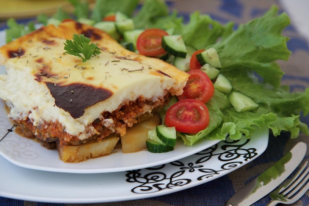 Prato grego tradicional com carne picada - moussaka. Servido com legumes frescos.