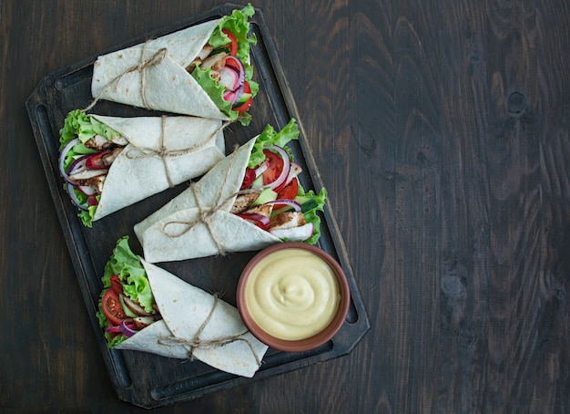 Prato mexicano. Taco com frango e legumes close-up sobre uma superfície de madeira.