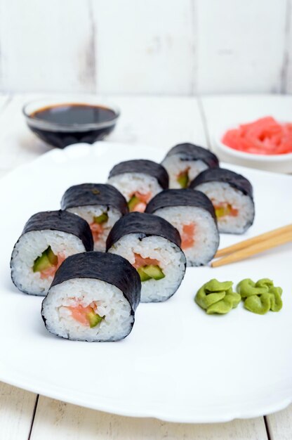 Prato oriental tradicional com sushi de salmão rola em um prato branco Closeup