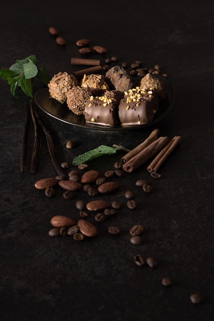 Prato pequeno cheio de bombons de chocolate amargo feitos à mão, decorados com nozes, canela, menta e café
