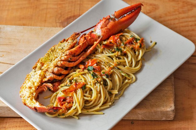 Prato retangular com muito espaguete e meia lagosta
