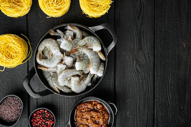 Prato tradicional italiano. conjunto de macarrão com pesto de ricota parmesão e ingredientes de frutos do mar grelhados, em fundo preto de madeira, vista de cima plana, com espaço de cópia para o texto