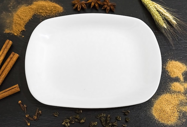 Prato vazio branco sobre uma mesa de madeira leve com alimentos decorativos ao redor