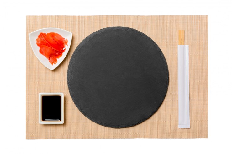 Foto prato vazio com pauzinhos para molho de sushi e soja, gengibre no fundo de esteira de sushi marrom. vista superior com espaço de cópia para você projetar