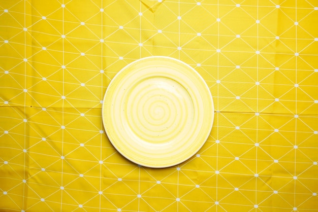Prato vazio em uma vista superior de uma toalha de mesa de cor amarela