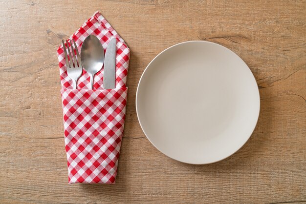 prato vazio ou prato com faca, garfo e colher em ladrilho de madeira