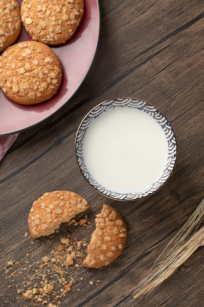 Prato vermelho com biscoitos de aveia e tigela de leite fresco na mesa de madeira