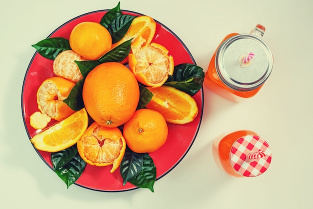 Prato vermelho com laranjas e tangerinas verde folhas garrafa com suco