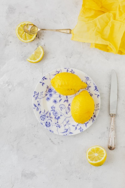 Prato vintage com limões em guardanapo amarelo de fundo branco e faca e colher vintage