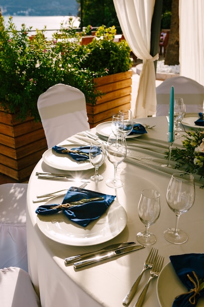 Pratos brancos de recepção de mesa de jantar de casamento com guardanapos de pano azul copos de vidro velas azuis