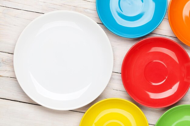 Pratos coloridos sobre fundo de mesa de madeira branca