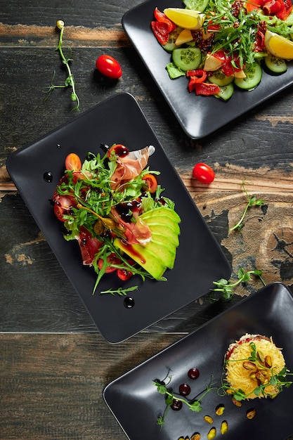 Pratos com saladas de vegetais frescos na mesa de madeira