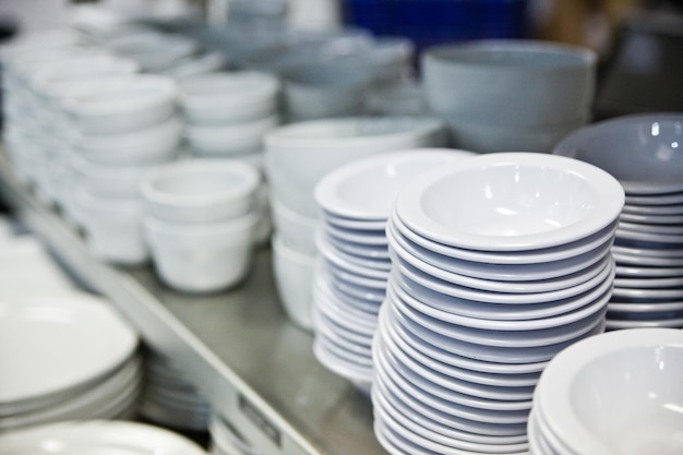 Pratos de cerâmica de cozinha comerciais empilhados em prateleiras metálicas