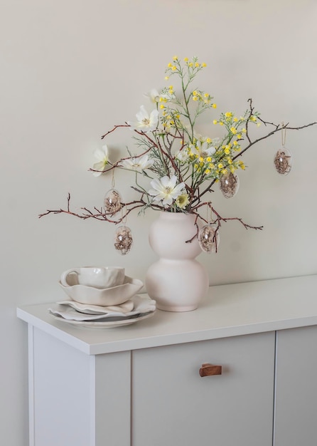 Pratos de mesa brancos de cerâmica decoração de páscoa bouquet de páscua em um buffet de madeira branca na sala de estar conceito de humor de férias