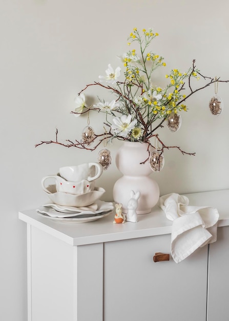 Foto pratos de mesa brancos de cerâmica decoração de páscoa buquê de páscua em uma gaveta de madeira branca na sala de estar humor de férias