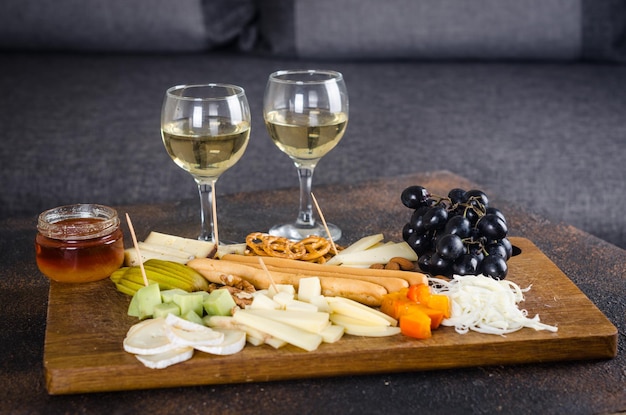 Pratos de queijo servidos com biscoitos de geléia de uvas e nozes em uma placa de madeira