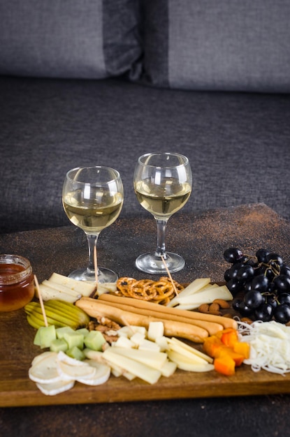 Pratos de queijo servidos com biscoitos de geléia de uvas e nozes em uma placa de madeira