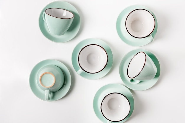 Pratos limpos, café ou chá. Abundância de elegantes xícaras e pires de porcelana azul claro, tonalidade alta, vista de cima e disposição plana.