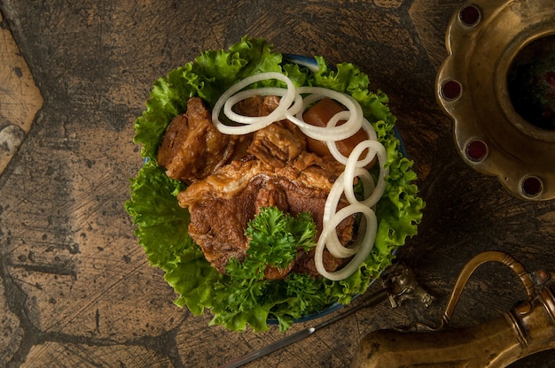 Pratos orientais em azulejos antigos decorativos. carne frita e jarro em pedras decorativas de pavimentação