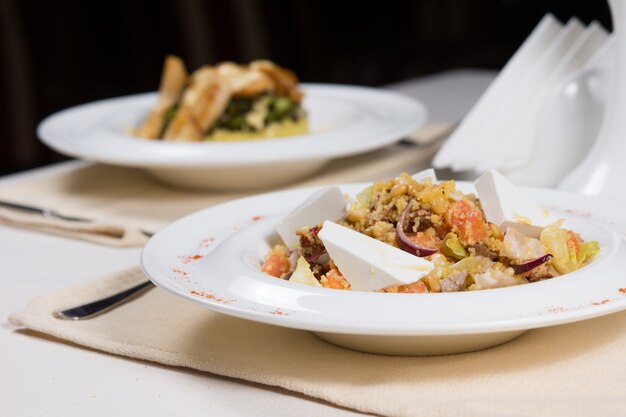 Pratos preparados em tigelas brancas em talheres simples servidos na mesa do restaurante para dois