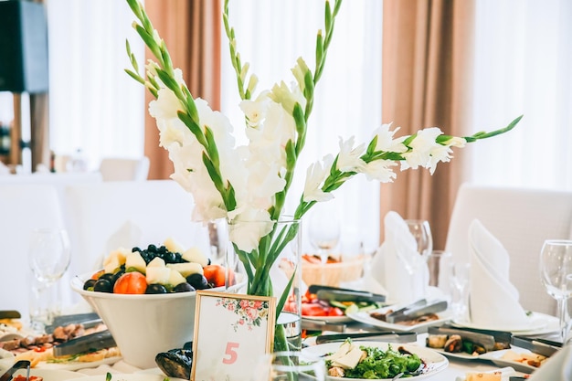 Pratos saborosos na recepção do casamento Flores brancas nas mesas