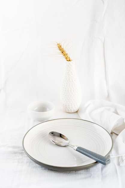 Foto pratos servindo em casa para comer. prato vazio e colher na mesa em um pano branco. visão vertical