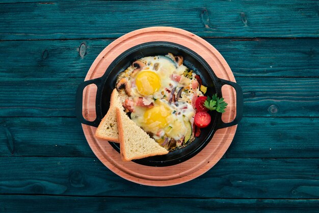 Pratos tradicionais da cozinha israelense Shakshuka Ovos com bacon e cogumelos Em um fundo de madeira Espaço livre para texto Vista superior