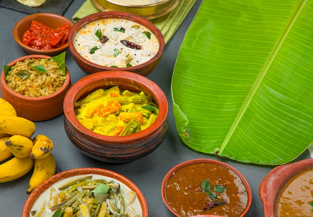 Foto pratos tradicionais de festa de kerala dispostos em um fundo de duas cores com folha de bananeira para servir comida