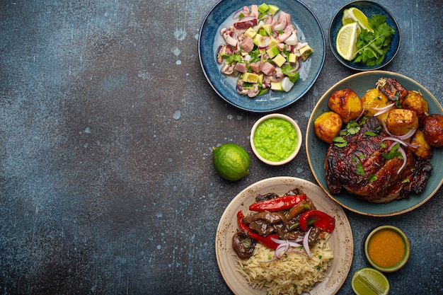 Pratos variados da culinária peruana: carne e pimentão lomo saltado, ceviche peruano com peixes e frutos do mar, frango assado e batata frita, molho de molho em mesa de pedra rústica de cima copy space