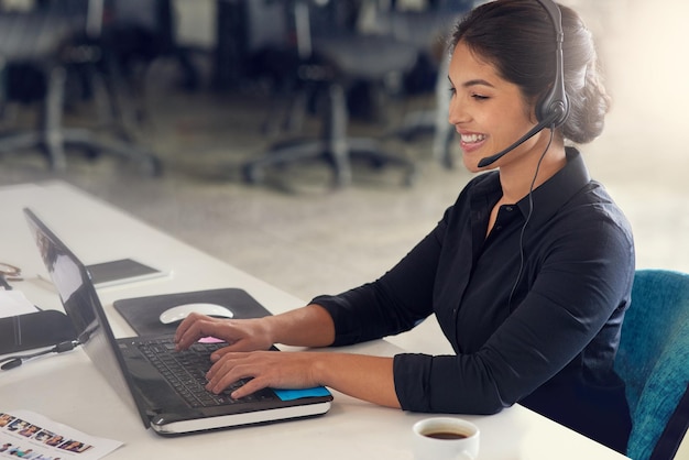 Prazer em ajudar Foto de uma agente de call center sentada em sua mesa em um escritório moderno