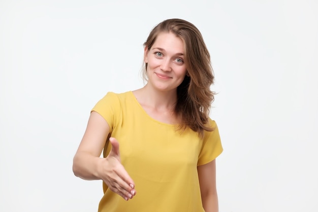 Prazer em conhecê-lo Retrato de aperto de mão de linda jovem emocional em camiseta amarela