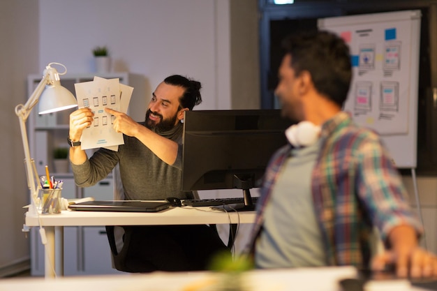 Foto prazo de negócios e web design pessoas conceito feliz homem criativo mostrando papéis para colega no escritório à noite