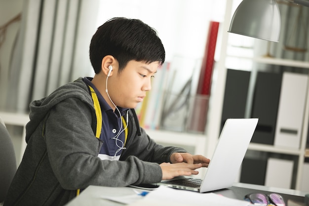 Pré-adolescentes asiáticos fazendo sua lição de casa com o laptop.