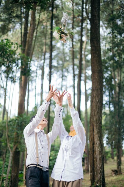 Foto pre-boda con concepto blanco y arrojando flores vista trasera de la mujer de pie en el bosque