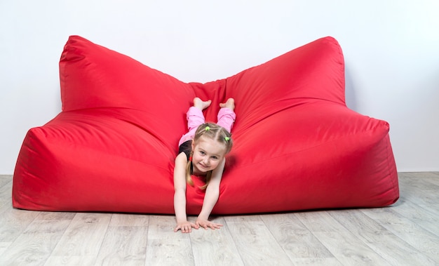 Pré-escolar menina deitada no grande sofá vermelho