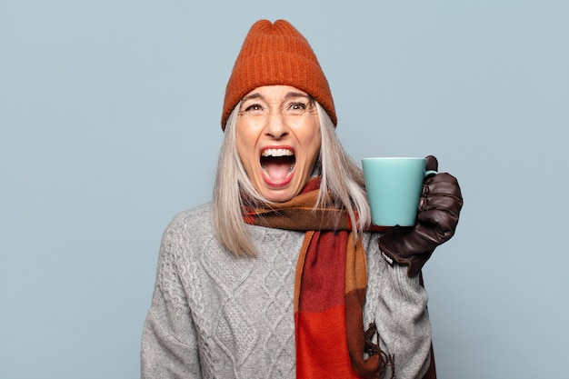 Pré-mulher sênior com uma xícara de café, vestindo roupas de inverno. conceito de inverno