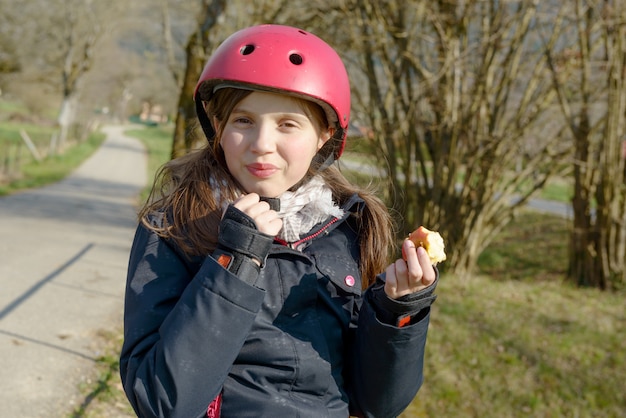 Foto preadolescente con casco de skate, come una manzana